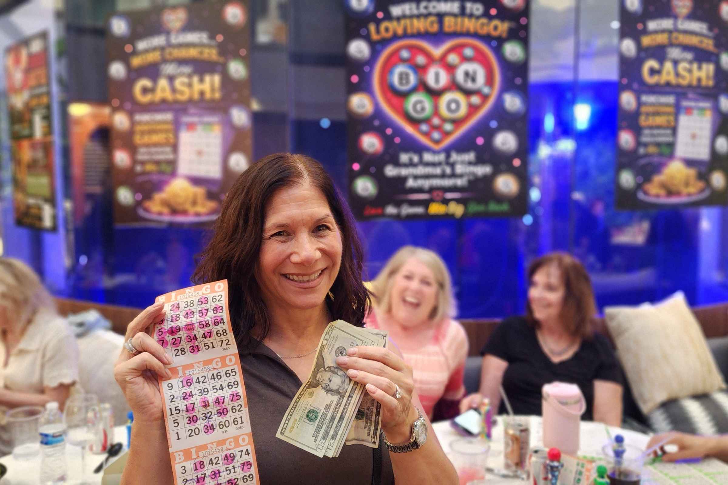 Winner holding cash and bingo cards at Loving Bingo night in Boca Raton at The Vine Restaurant & Bar